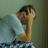 Photo of distressed man sitting on bed