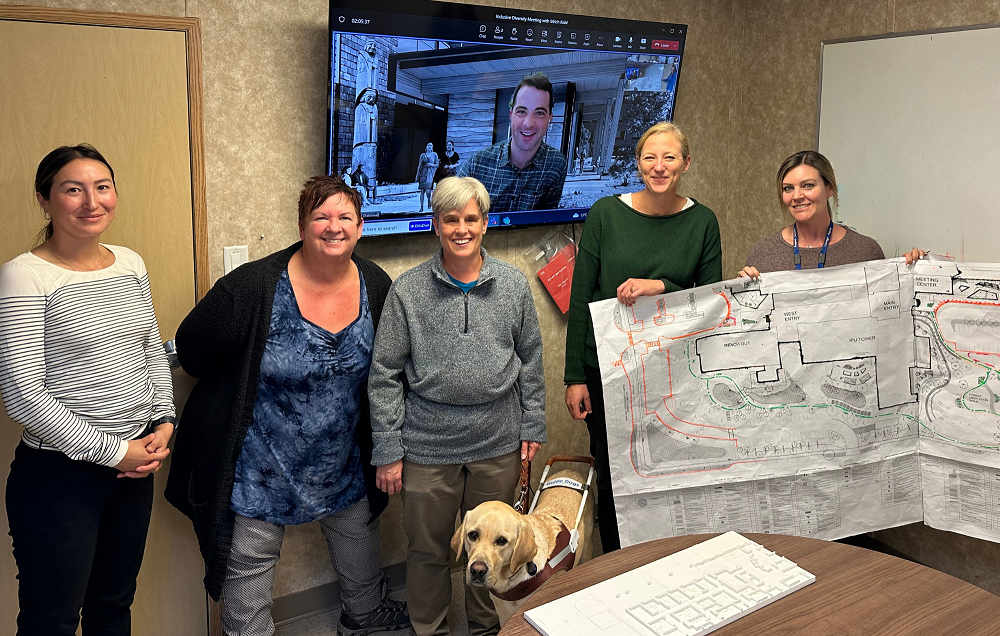 Above, left to right: Itel, Janeen, Mitch – and special team member Mario (a yellow Labrador retriever guide dog), Scott (on video monitor behind the group), Tam and Jody, from the Project’s Inclusive Diversity Focus Group. On the table in foreground is a low-relief 3-D model of the Emergency Department entrance/triage area. Tam and Jody are holding the landscape drawing outlined with raised glue to enable a tactile tour of the new hospital’s exterior spaces.