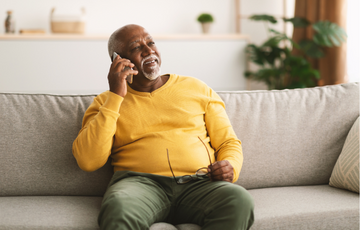 An older man using his phone while sitting on a couch
