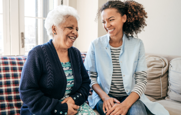 a senior woman and a younger female sitting on a couch