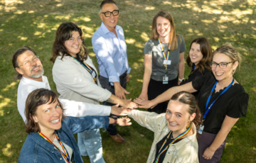 Several people bringing their hands into the middle of a huddle