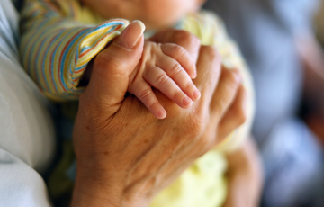 Senior holding hands with infant