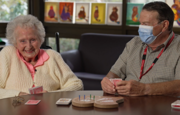 Senior patient playing cards with volunteer at table